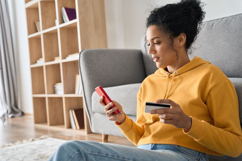 woman using a phone while holding a card